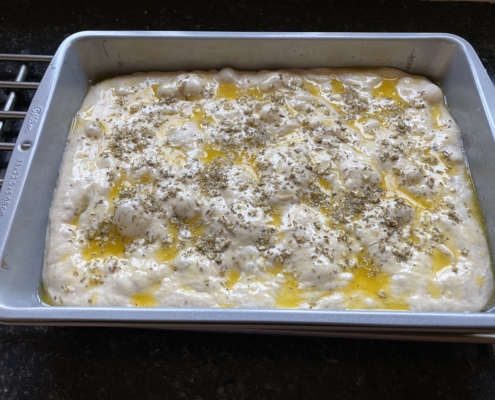 Sourdough garlic and her focaccia in baking tray waiting to be cooked